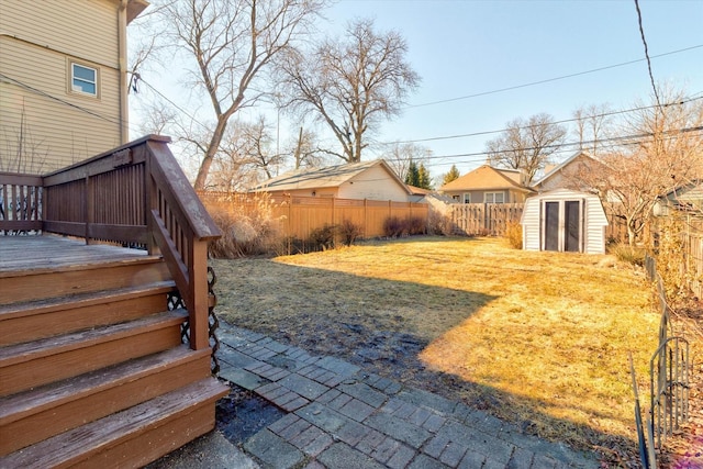 view of yard with a fenced backyard, a storage unit, an outbuilding, and a wooden deck