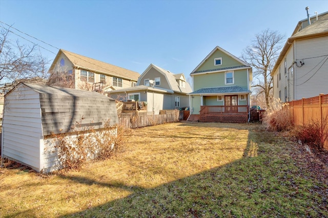 rear view of house featuring a deck, a yard, an outdoor structure, and a fenced backyard