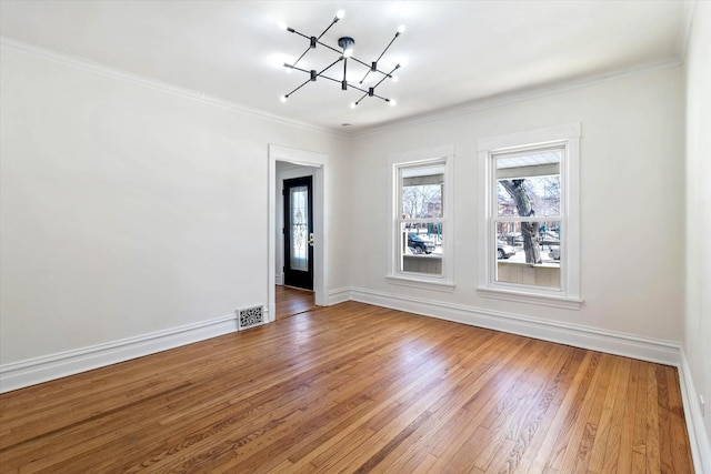 empty room featuring a chandelier, visible vents, baseboards, hardwood / wood-style floors, and crown molding