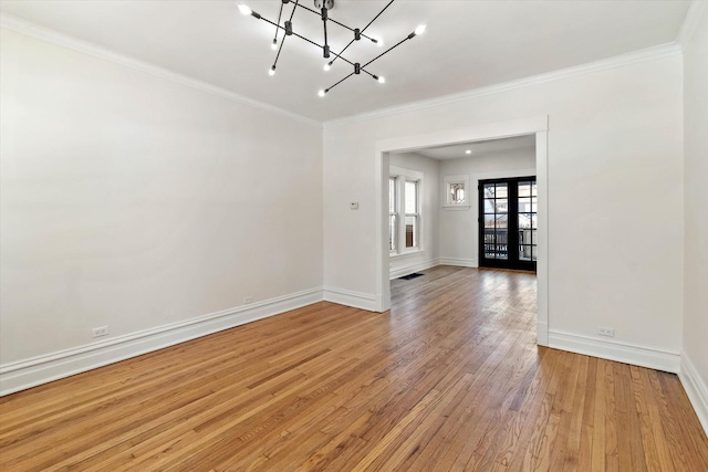 empty room featuring baseboards, hardwood / wood-style flooring, an inviting chandelier, crown molding, and french doors