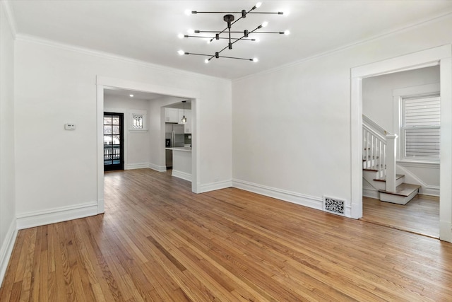 unfurnished room with stairway, light wood-type flooring, visible vents, and crown molding