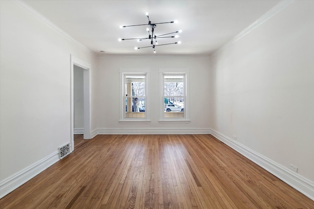 spare room featuring baseboards, wood-type flooring, visible vents, and crown molding