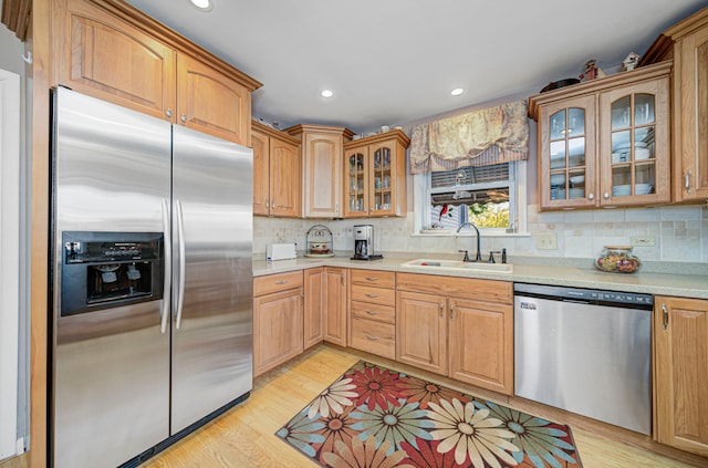 kitchen featuring sink, appliances with stainless steel finishes, light hardwood / wood-style flooring, and tasteful backsplash