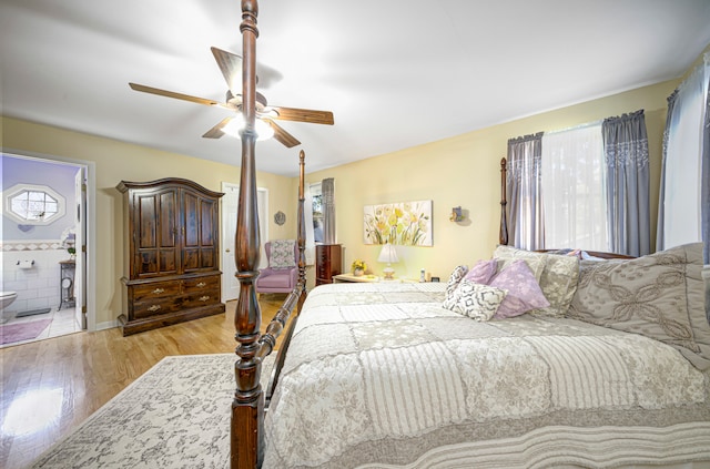 bedroom with ensuite bathroom, light hardwood / wood-style floors, and ceiling fan