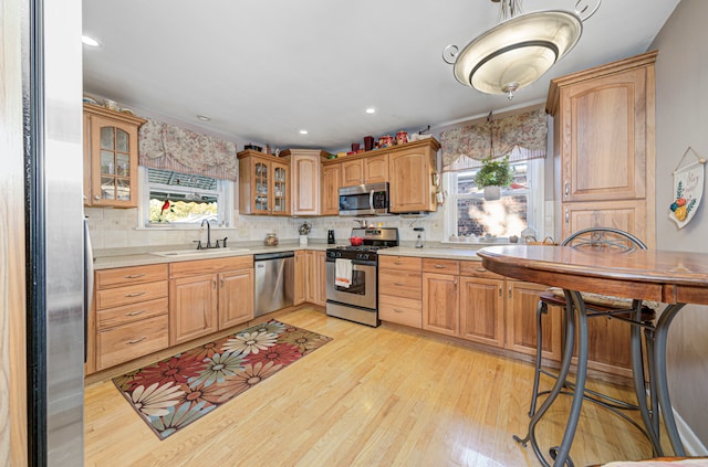 kitchen featuring tasteful backsplash, appliances with stainless steel finishes, sink, and light wood-type flooring