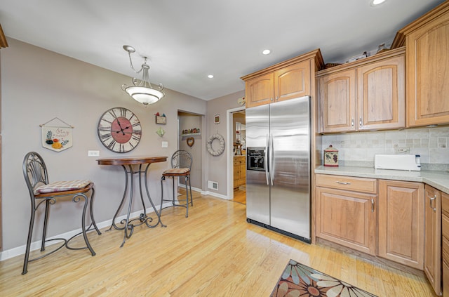 kitchen with stainless steel fridge with ice dispenser, light hardwood / wood-style flooring, decorative light fixtures, and backsplash