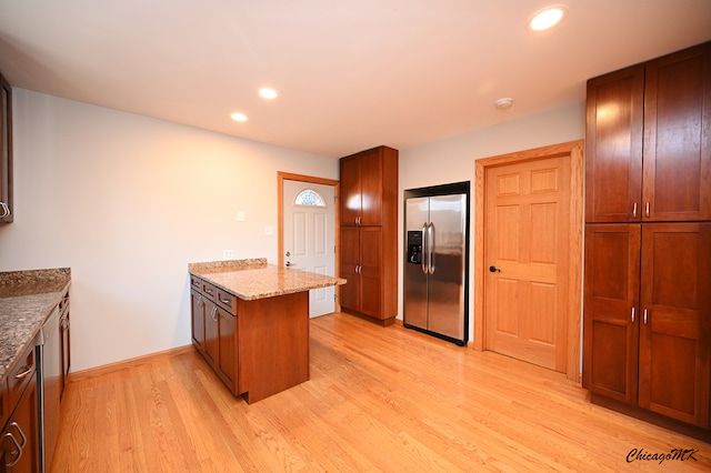 kitchen with kitchen peninsula, light stone counters, stainless steel appliances, and light hardwood / wood-style floors