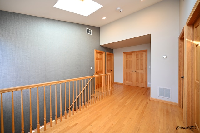 hall with light hardwood / wood-style floors and a skylight