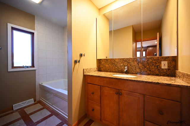 bathroom with vanity, backsplash, and a bathtub