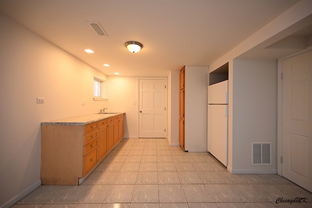 kitchen with white refrigerator, sink, and light tile patterned flooring