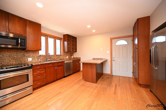 kitchen with light stone countertops, sink, light wood-type flooring, and appliances with stainless steel finishes