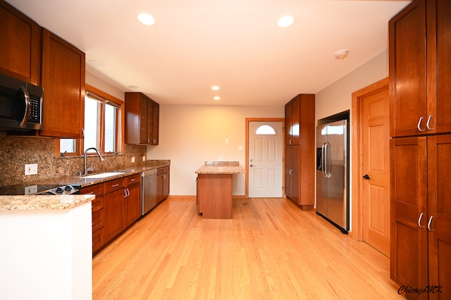 kitchen with backsplash, stainless steel appliances, light hardwood / wood-style flooring, and sink