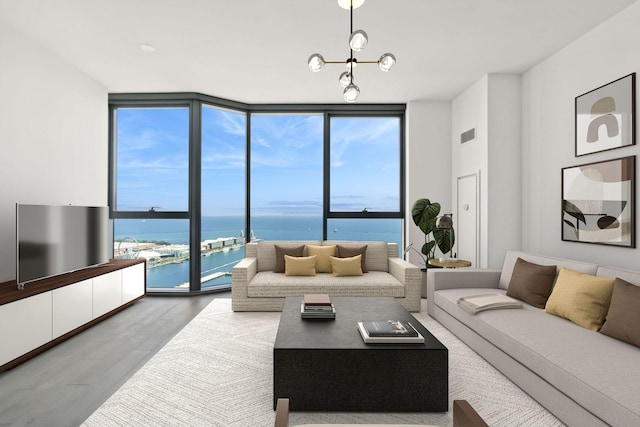 living room featuring hardwood / wood-style floors, a notable chandelier, floor to ceiling windows, and a water view