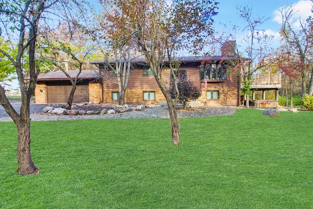 rear view of property featuring a garage and a lawn