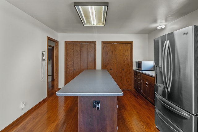 kitchen with stainless steel appliances, dark brown cabinets, dark hardwood / wood-style flooring, and a kitchen island