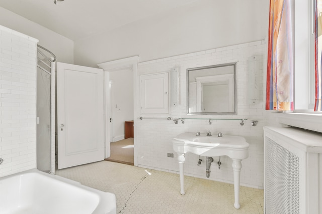 bathroom with radiator heating unit, tile walls, and a bath