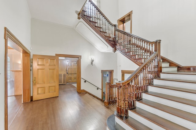 stairway with a wealth of natural light, wood-type flooring, and a towering ceiling