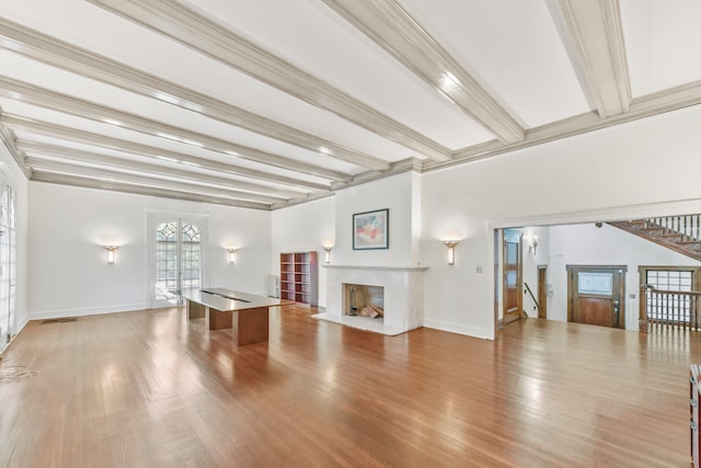 unfurnished living room featuring beamed ceiling, hardwood / wood-style floors, ornamental molding, and a high end fireplace