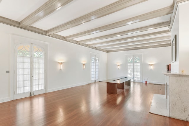 unfurnished living room featuring french doors, hardwood / wood-style flooring, beamed ceiling, and a fireplace