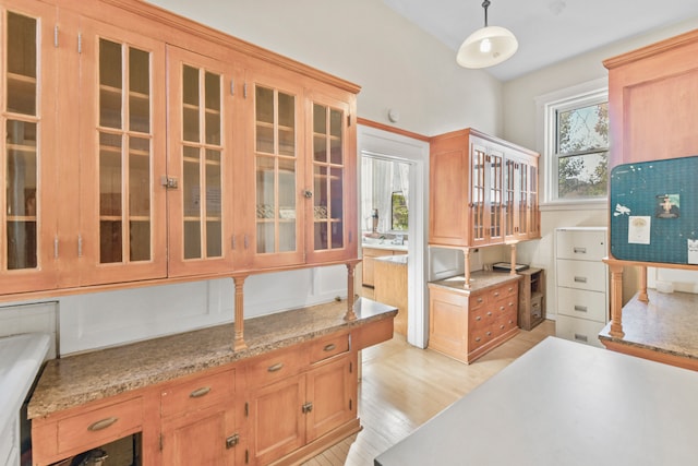 kitchen featuring light stone counters, hanging light fixtures, and light wood-type flooring