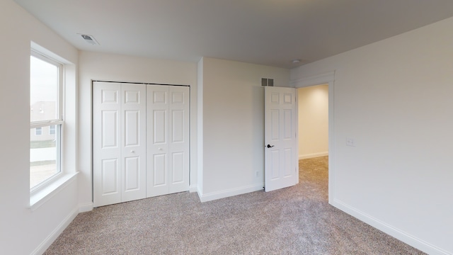 unfurnished bedroom featuring light carpet, multiple windows, and a closet