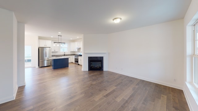 unfurnished living room with sink and hardwood / wood-style floors