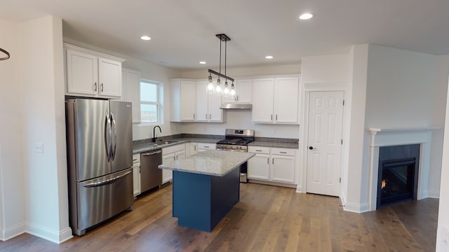 kitchen with white cabinets, hanging light fixtures, dark hardwood / wood-style flooring, appliances with stainless steel finishes, and a kitchen island