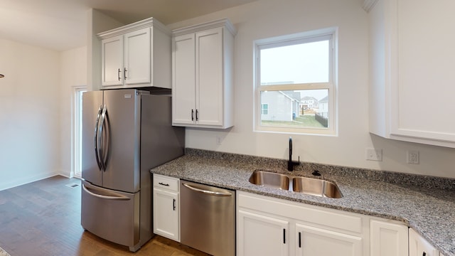 kitchen featuring dark hardwood / wood-style floors, stainless steel appliances, sink, stone counters, and white cabinetry