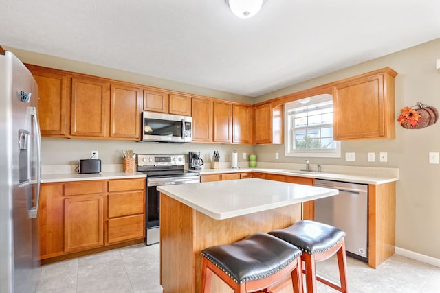 kitchen with sink, light tile patterned flooring, a kitchen island, stainless steel appliances, and a breakfast bar