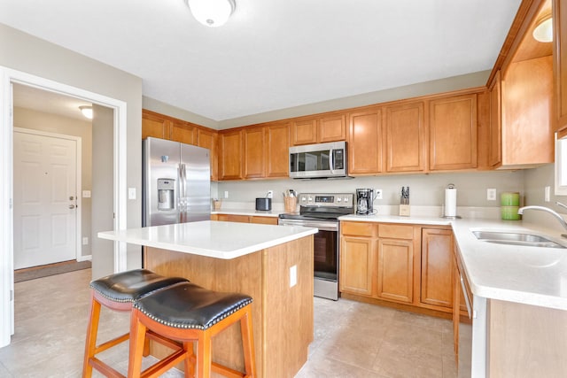 kitchen with a kitchen island, stainless steel appliances, sink, light tile patterned flooring, and a kitchen bar