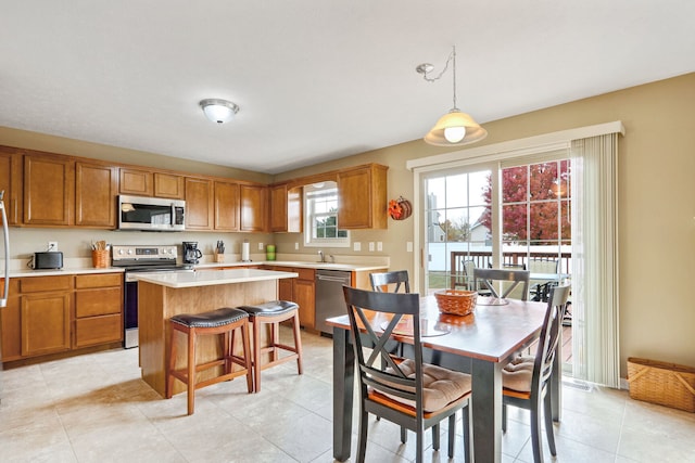 kitchen with a center island, a kitchen bar, pendant lighting, light tile patterned floors, and appliances with stainless steel finishes