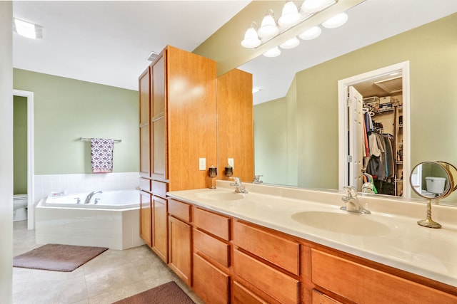 bathroom featuring toilet, a relaxing tiled tub, vanity, and tile patterned flooring