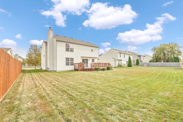 rear view of property featuring a yard and a deck