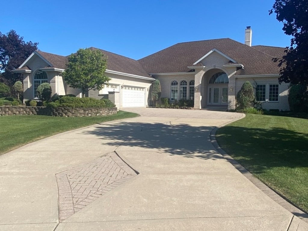 ranch-style house featuring french doors, a front lawn, and a garage