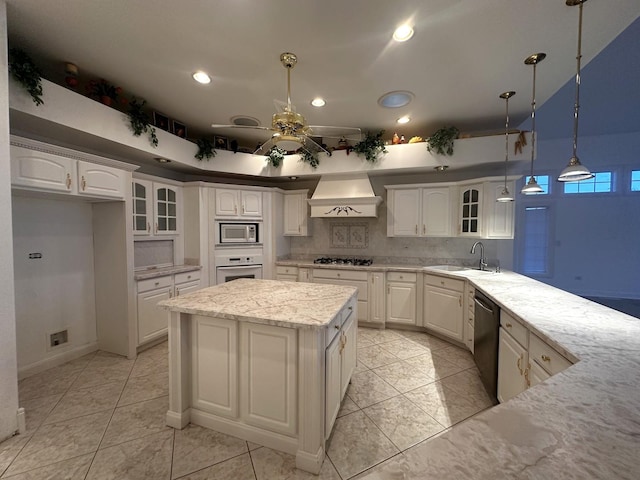 kitchen with premium range hood, hanging light fixtures, sink, appliances with stainless steel finishes, and white cabinetry