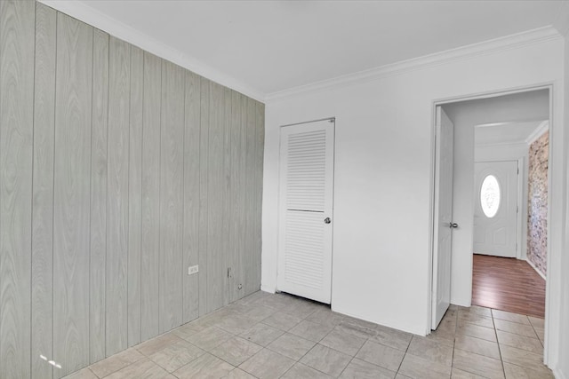 unfurnished bedroom with ornamental molding, light wood-type flooring, and wood walls