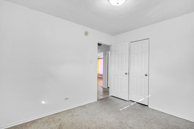 unfurnished bedroom featuring a closet and light colored carpet