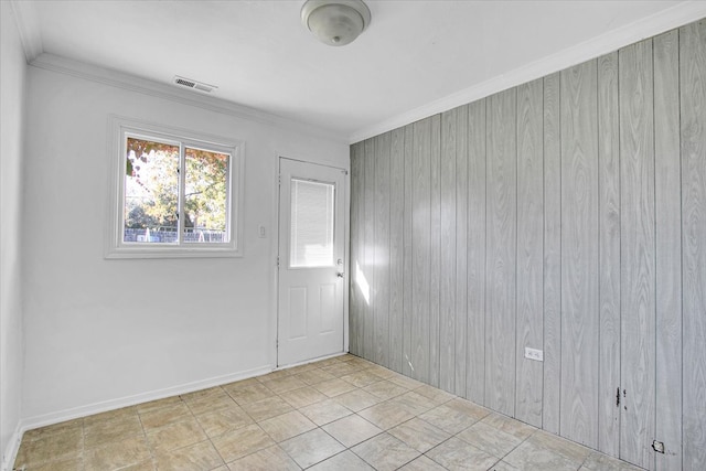 spare room with crown molding and wooden walls