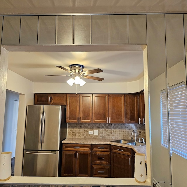 kitchen with sink, ceiling fan, tasteful backsplash, and stainless steel refrigerator