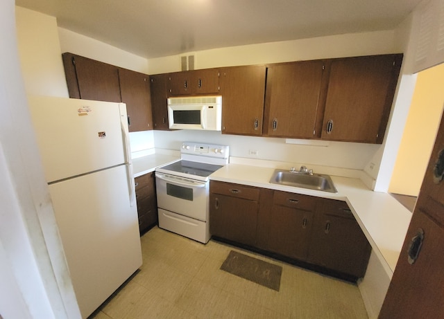 kitchen with white appliances, dark brown cabinets, and sink