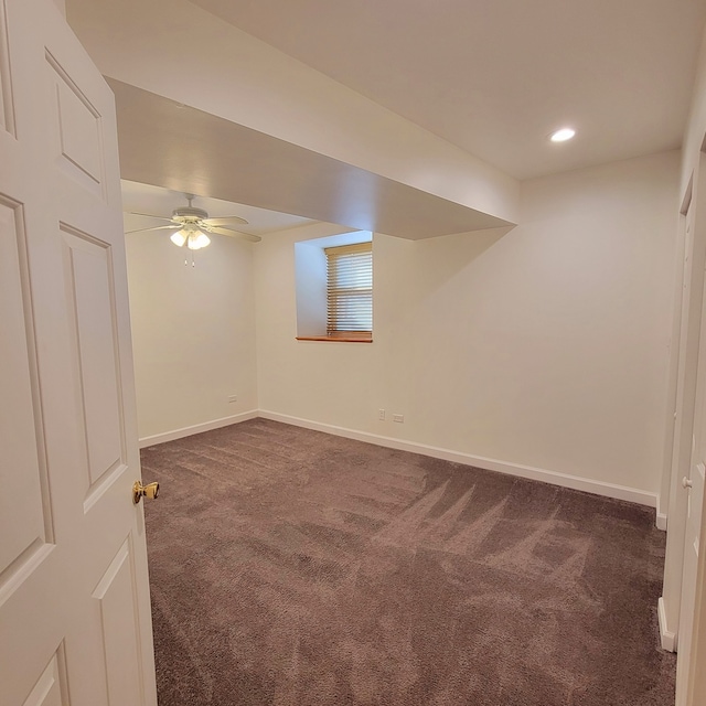 basement with ceiling fan and dark colored carpet