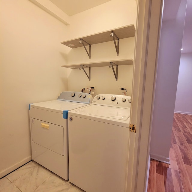 laundry area with washer and clothes dryer and light hardwood / wood-style floors