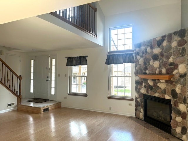 unfurnished living room featuring a wealth of natural light, a stone fireplace, and wood-type flooring