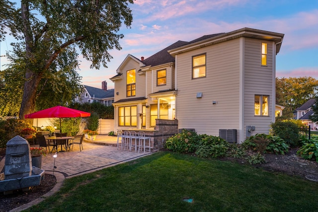 rear view of property featuring cooling unit, a patio area, a lawn, and fence