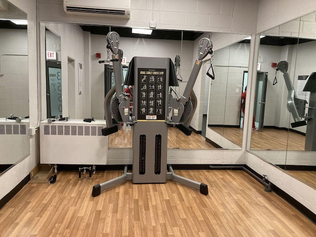 gym featuring radiator, a wall mounted AC, and light hardwood / wood-style floors