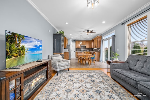 living room featuring light hardwood / wood-style flooring, ceiling fan, and crown molding