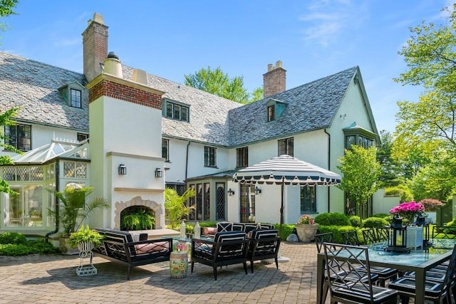 rear view of property with exterior fireplace and a patio area