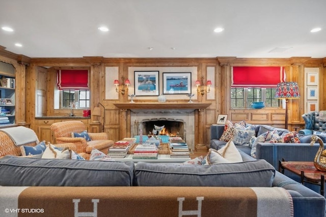 living room featuring a high end fireplace, wooden walls, sink, and a wealth of natural light