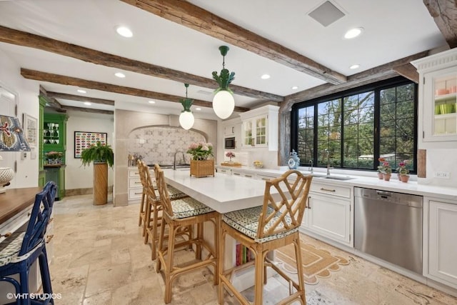 kitchen with pendant lighting, beamed ceiling, white cabinetry, dishwasher, and a breakfast bar area