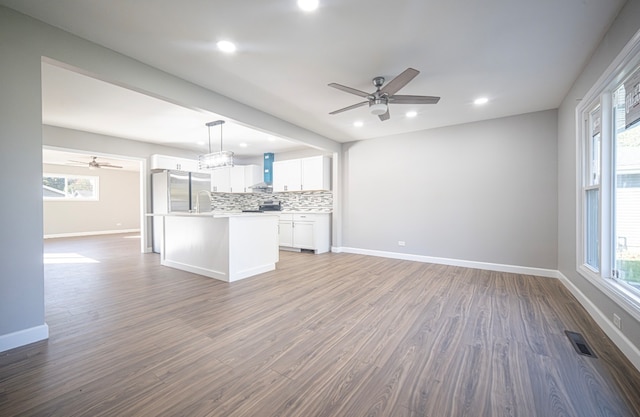 kitchen featuring wall chimney range hood, white cabinetry, and a healthy amount of sunlight